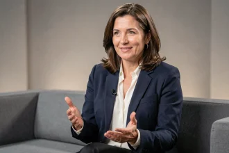 Femme journaliste française en interview télévisée dans un studio moderne, blazer marine et chemisier blanc, expression assurée