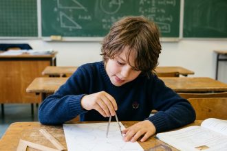 Élève concentré utilisant un compas sur une feuille de géométrie dans une salle de classe