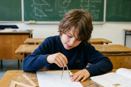 Élève concentré utilisant un compas sur une feuille de géométrie dans une salle de classe