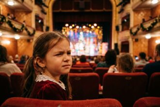 Petite fille plissant les yeux pendant un spectacle de Noël pour enfants dans un théâtre